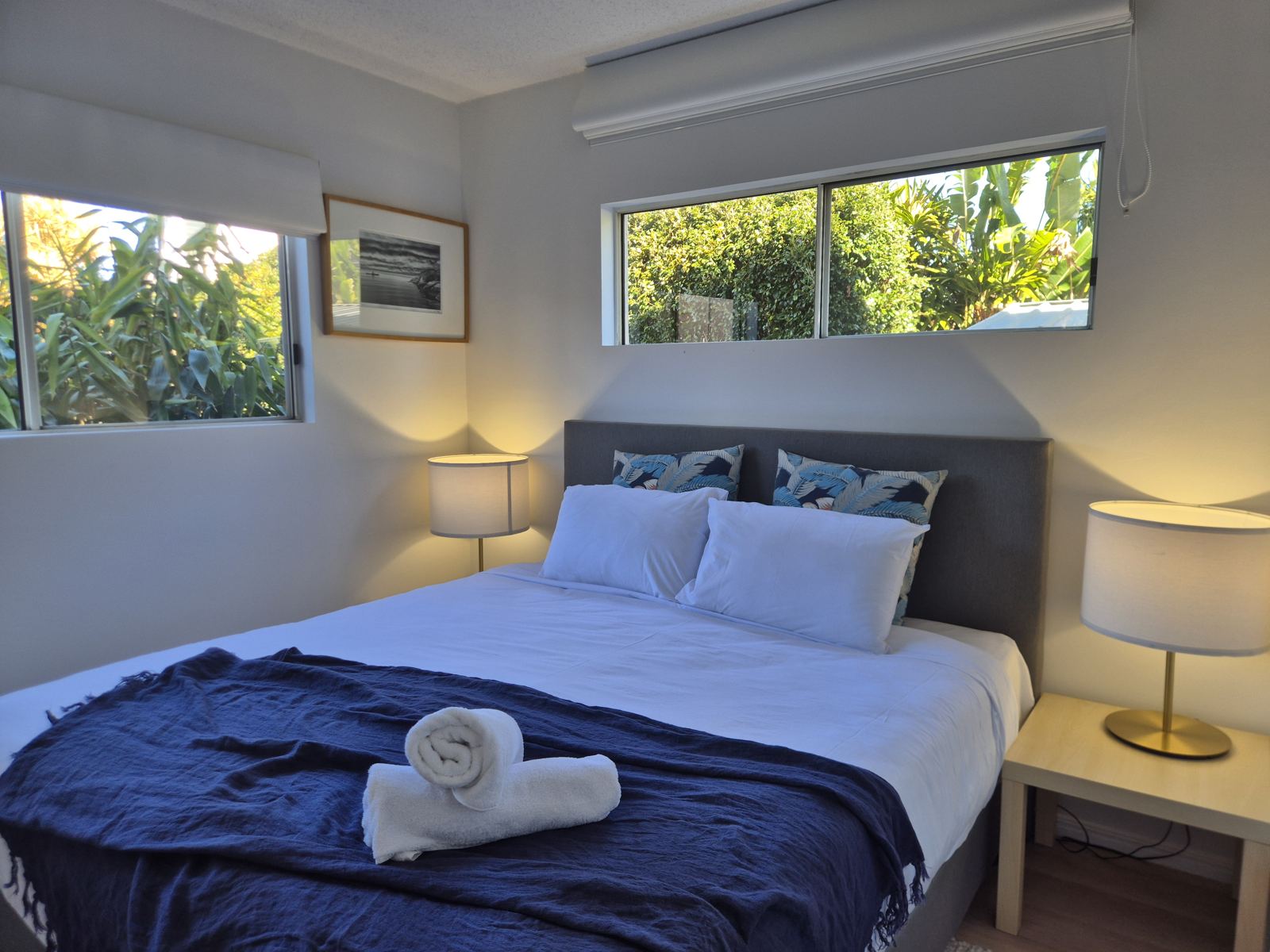 Canal View bedroom with king bed, navy throw, bedside lamps and garden views through two windows