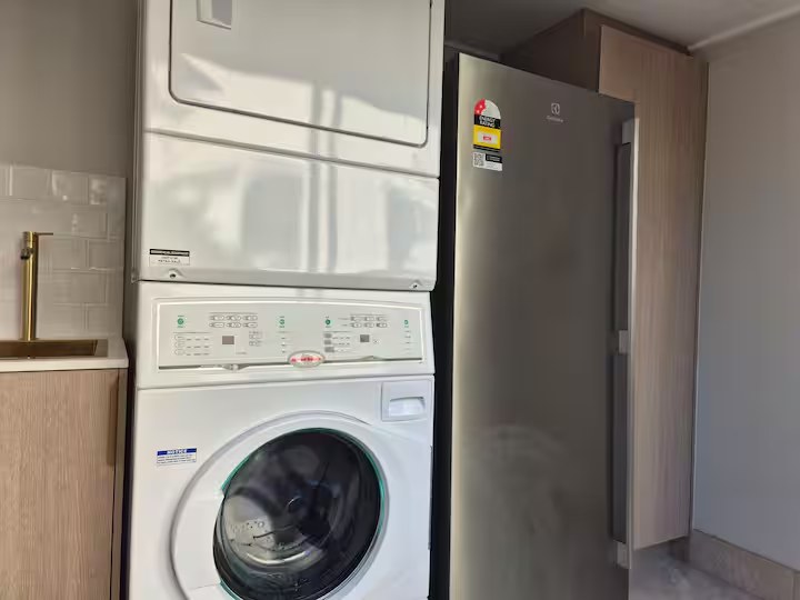 Renovated guest laundry with stacked washer and dryer and the communal freezer