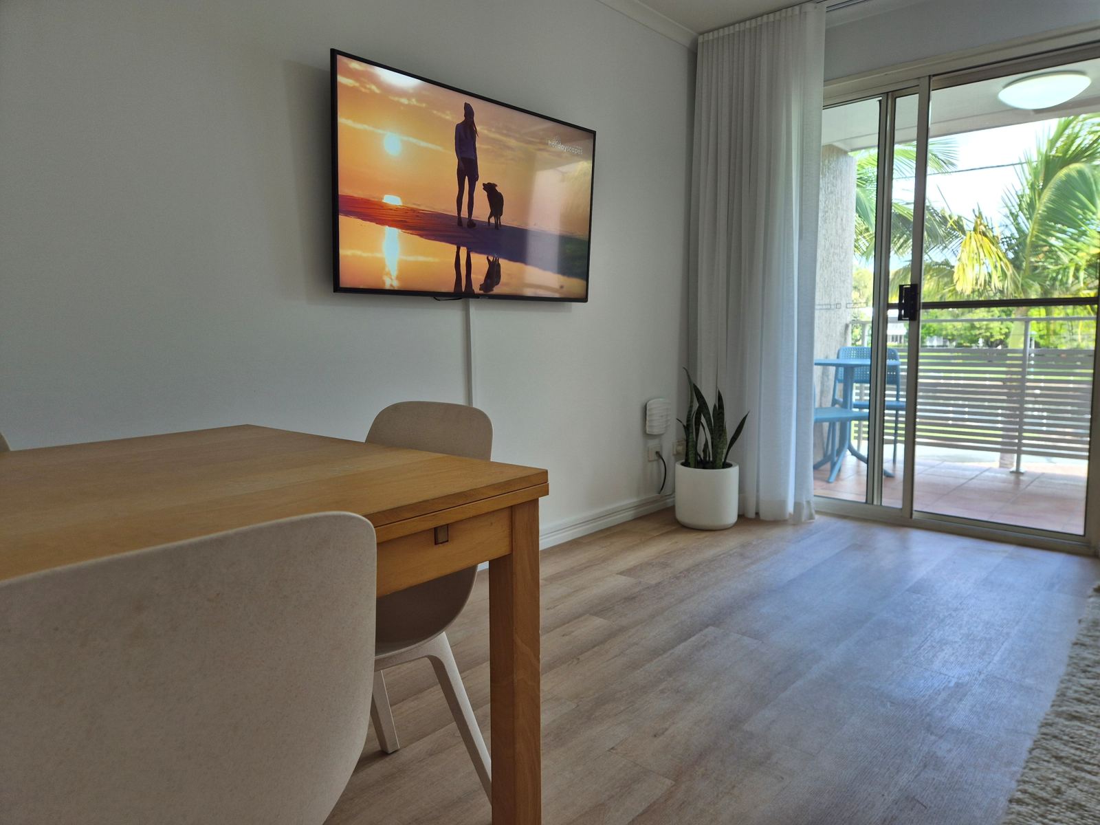 Dining table and wall-mounted Smart TV, with sliding doors to the balcony