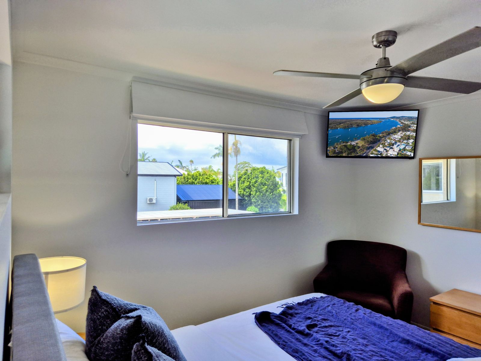 Bedroom with king bed, armchair, wall-mounted TV and ceiling fan