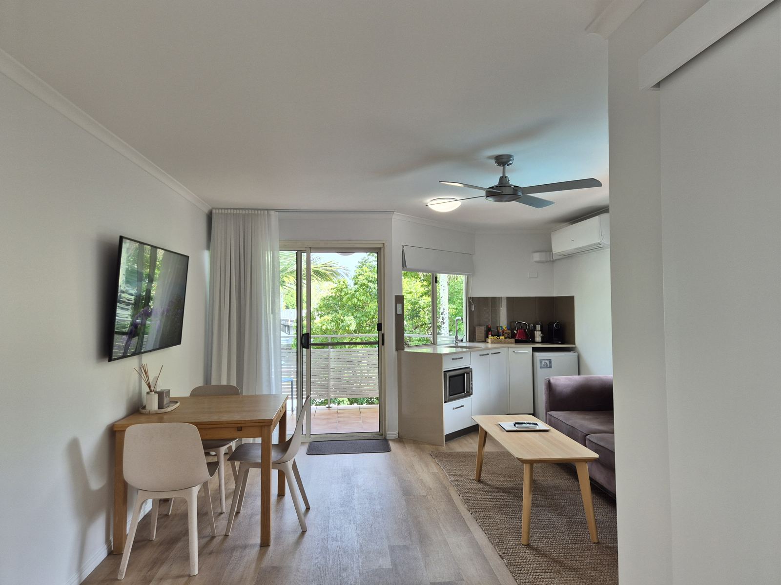 Open-plan living with dining table, kitchenette and balcony doors